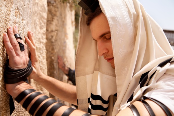 A Jewish man prays at the Western (Wailing) Wall wearing tefillin (phylacteries). (Photo credit: Go Israel, Noam Chen)
