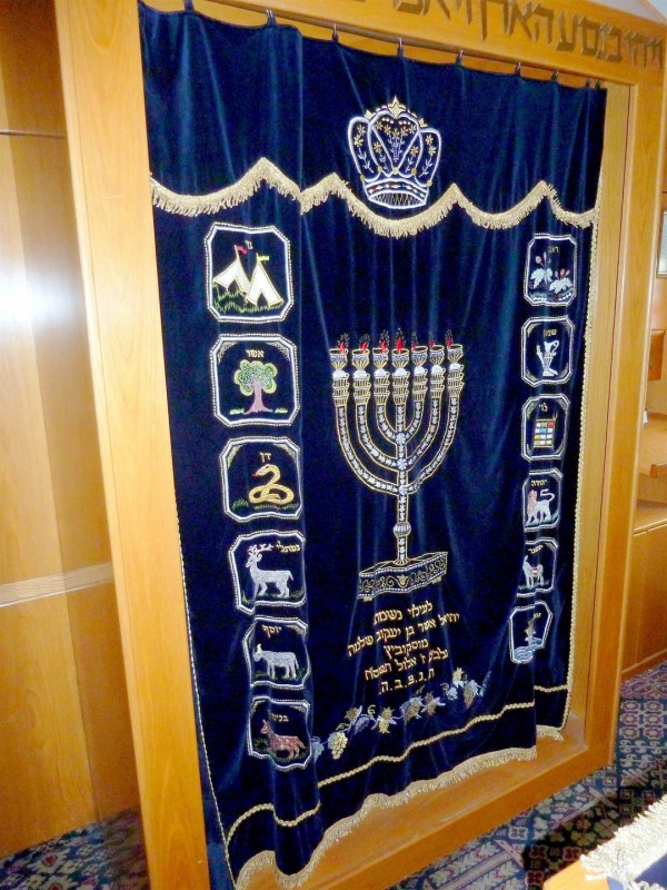 The parokhet that today covers the Torah Ark represents the Parokhet that once hung at the entrance to the Holy of Holies where the Ark of the Covenant was held. This parokhet is embroidered with symbols of the Tribes of Israel and with the Menorah. The parokhet that today covers the Torah Ark represents the Parokhet that once hung at the entrance to the Holy of Holies where the Ark of the Covenant was held. This parokhet is embroidered with symbols of the Tribes of Israel and with the Menorah.