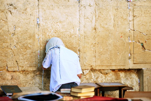 A Jewish man prays at the Western (Wailing) Wall with his tallit (prayer shawl) pulled over his head. A Jewish man prays at the Western (Wailing) Wall with his tallit (prayer shawl) pulled over his head.